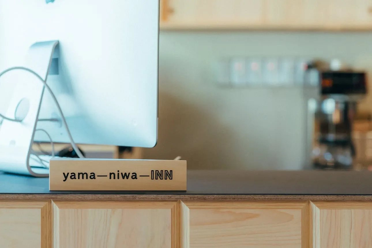 「yama—niwa—INN」の木製サインが置かれたカウンター