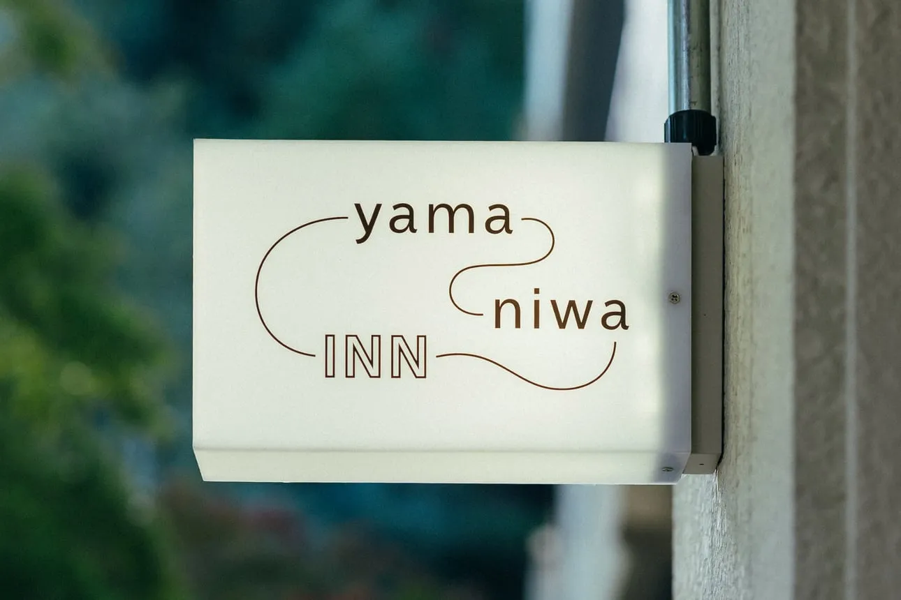 「yama niwa INN」のロゴが入った壁掛けサイン